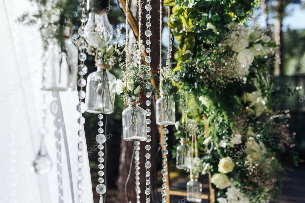 The wedding arch is decorated with beautiful decorative bouquets in jars