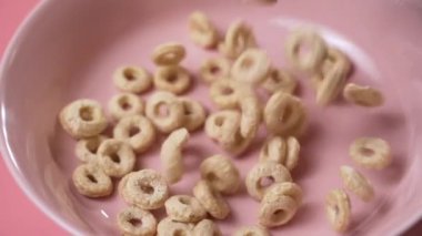 Kahvaltı gevreği halkaları pembe tabağa düşer.