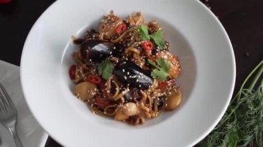 Kamera, güzel dekore edilmiş deniz ürünleri makarnasını beyaz tabakta döndürür.