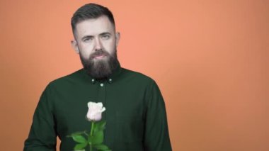 Elinde gül olan yeşil tişörtlü sakallı adam Sevgililer Günü 'nü kutluyor.