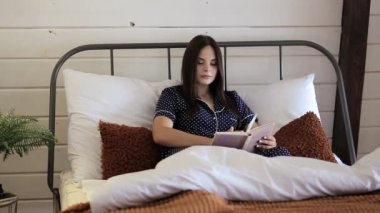 Yatakta uzanmış kitap okuyan güzel kız.