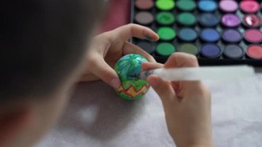 Yakın plan, bir çocuk Paskalya yumurtası boyuyor.