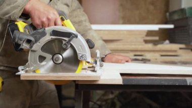 Oduncu dairesel testere ile tahta kesiyor.