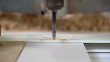 Bir sondaj makinesi tahta bir levhada delik açar.