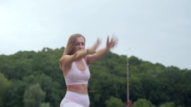 Kadın yoga yapıyor, bacaklarını açıyor ve arkasını kolluyor.