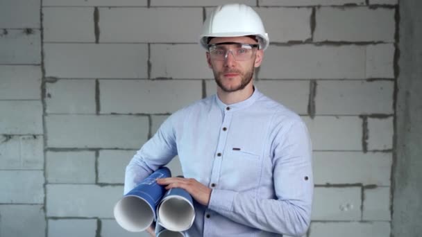 Portrait of a builder with an armful of construction plans looking at the camera in front of him