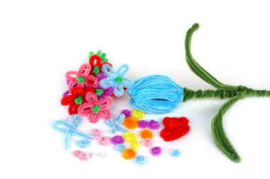 Colorful pipe cleaner flowers and shapes arranged on white background, representing DIY craft materials, creativity, art supplies, handmade decoration, and fun learning activities for children.                               
