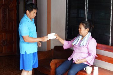 Asyalı orta yaşlı bir adam yaşlı bir kadına koruyucu yüz maskesi veriyor. Konsept, aile bakımı, hijyen ve solunum hastalıklarının önlenmesi. Temel olarak evde hasta bakımı..                               