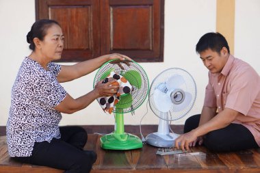  Yaşlı bir kadın ve bir erkek evdeki elektrikli vantilatörleri temizlemek ve onarmak için birlikte çalışırlar. Takım çalışması, bakım ve pratik ev bakımını her gün sıcak bir ortamda gösterirler..                              