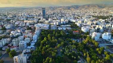 Kıbrıs Rum Kesimi 'nin Limasol kentinin hava panoramik manzarası, modern ufuk çizgisi, yerleşim alanları ve yeşil alanları vurguluyor. Görüntü canlı şehir yaşamını, kentsel gelişimi ve Akdeniz kıyı atmosferini yansıtıyor..