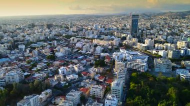 Kıbrıs Rum Kesimi 'nin Limasol kentinin hava panoramik manzarası, modern ufuk çizgisi, yerleşim alanları ve yeşil alanları vurguluyor. Görüntü canlı şehir yaşamını, kentsel gelişimi ve Akdeniz kıyı atmosferini yansıtıyor..