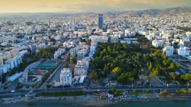 Kıbrıs Rum Kesimi 'nin Limasol kentinin hava panoramik manzarası, modern ufuk çizgisi, yerleşim alanları ve yeşil alanları vurguluyor. Görüntü canlı şehir yaşamını, kentsel gelişimi ve Akdeniz kıyı atmosferini yansıtıyor..