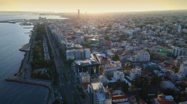 Kıbrıs Rum Kesimi 'nin Limasol kentinin hava panoramik manzarası, modern ufuk çizgisi, yerleşim alanları ve yeşil alanları vurguluyor. Görüntü canlı şehir yaşamını, kentsel gelişimi ve Akdeniz kıyı atmosferini yansıtıyor..