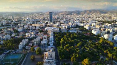 Kıbrıs Rum Kesimi 'nin Limasol kentinin hava panoramik manzarası, modern ufuk çizgisi, yerleşim alanları ve yeşil alanları vurguluyor. Görüntü canlı şehir yaşamını, kentsel gelişimi ve Akdeniz kıyı atmosferini yansıtıyor..