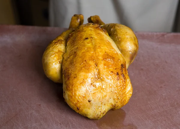 Pollo asado entero en una tabla de cortar con textura rústica — Foto de Stock