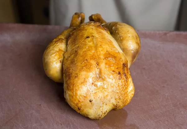 Pollo asado entero en una tabla de cortar con textura rústica — Foto de Stock