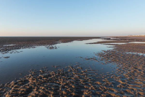 Kum dalgaları, kumsal taşları ve gökyüzünün su havuzuna yansıdığı güzel, güneşli bir İngiliz kumsalında kış günü.. — Stok fotoğraf
