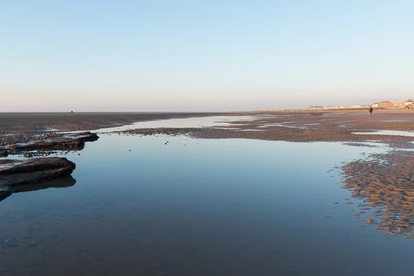 Belle journée d'hivers ensoleillés sur une plage britannique, avec des ondulations de sable, des pierres de plage et le ciel se reflétant dans une piscine d'eau . — Photo