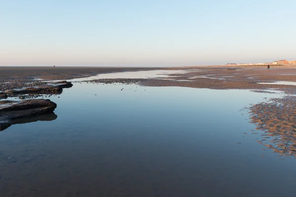 Belle journée d'hivers ensoleillés sur une plage britannique, avec des ondulations de sable, des pierres de plage et le ciel se reflétant dans une piscine d'eau . — Photo