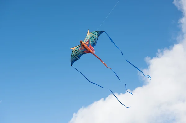 Mythical dragon kite flying in a cloudy sky on a bright sunny day — Stock Photo, Image