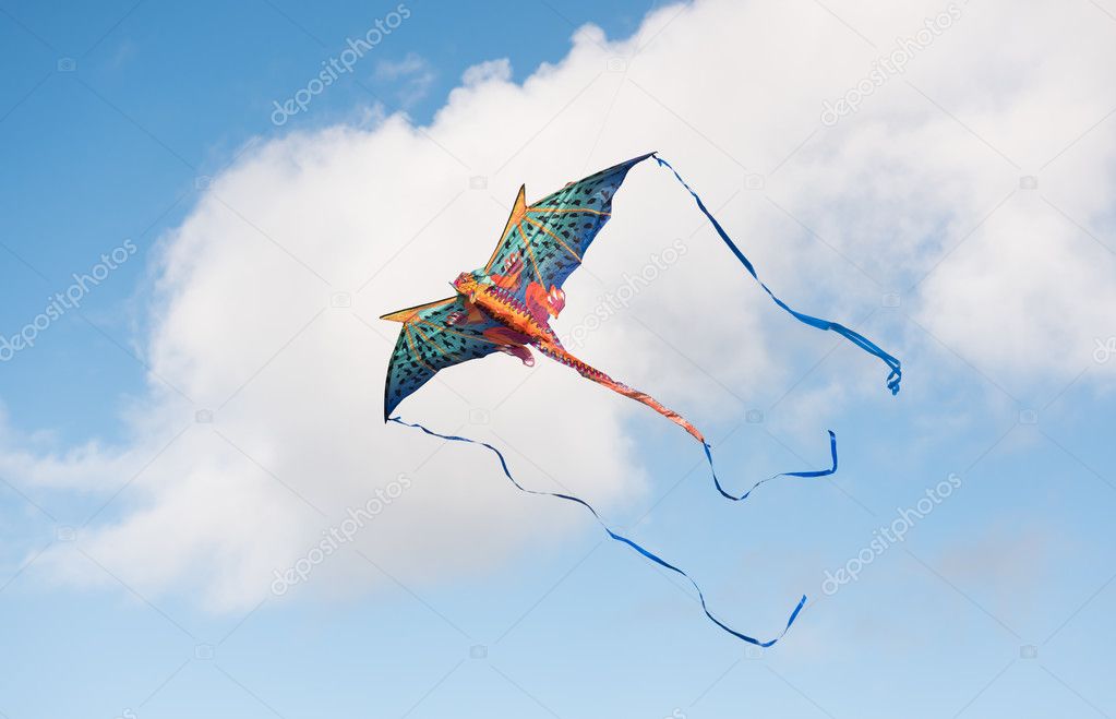 Mythical dragon kite flying in a cloudy sky on a bright sunny day