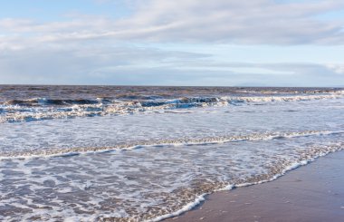 bir plaj gün batımında akan rahatlatıcı ve yumuşak yatıştırıcı dalgalar