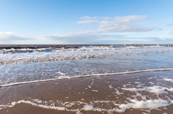 Avkopplande och mild lugnande vågor flyter in i en strand vid solnedgången — Stockfoto