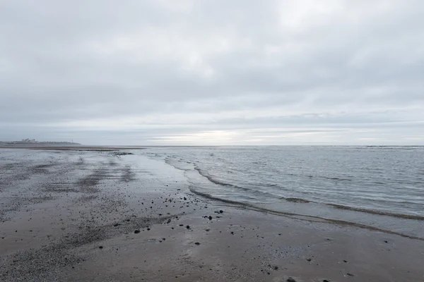 Entspannende und sanft beruhigende Wellen, die an einem trüben, bewölkten Tag in einen Strand fließen — Stockfoto