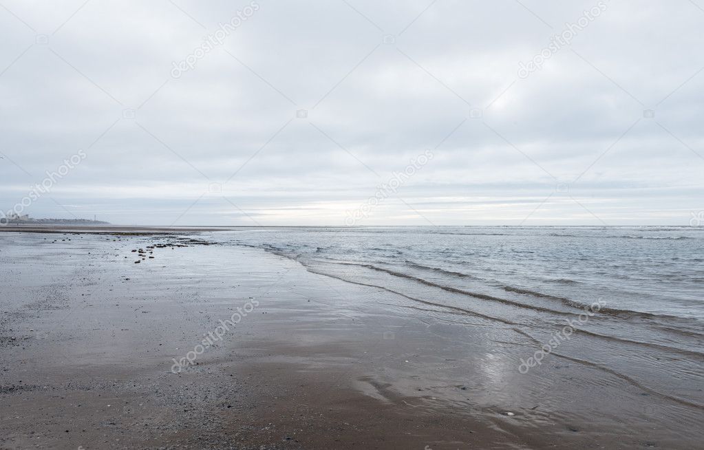 relaxing and gentle calming waves flowing into a beach on an gloomy overcast day