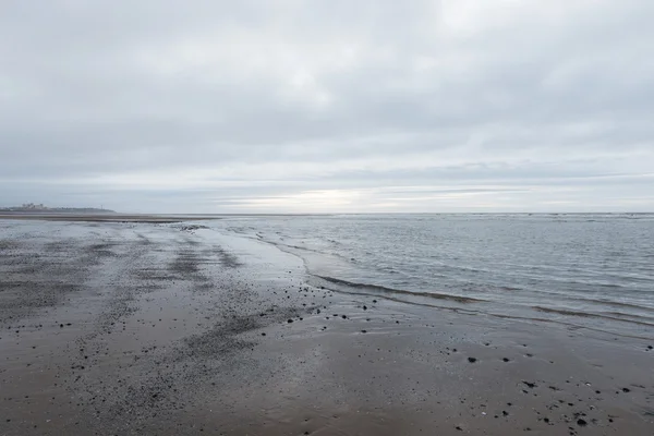 Relajantes y suaves olas tranquilizantes que desembocan en una playa en un sombrío día nublado —  Fotos de Stock