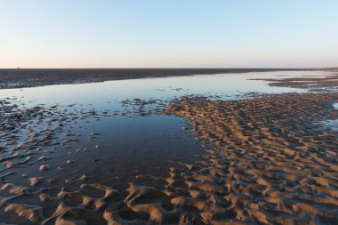 Kum dalgaların ve su havuzunda yansıtan gökyüzü ile bir İngiliz plaj güzel güneşli kış gününde.