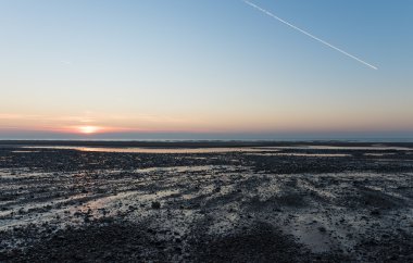 Beyaz Yoğunlaşma Patikası Sahilde uçan bir uçaktan Güzel mavi ve pembe günbatımı gökyüzünde 