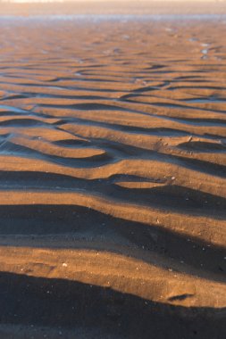 Gün batımında kum sıcak bir altın plajda dalgalanma dokular