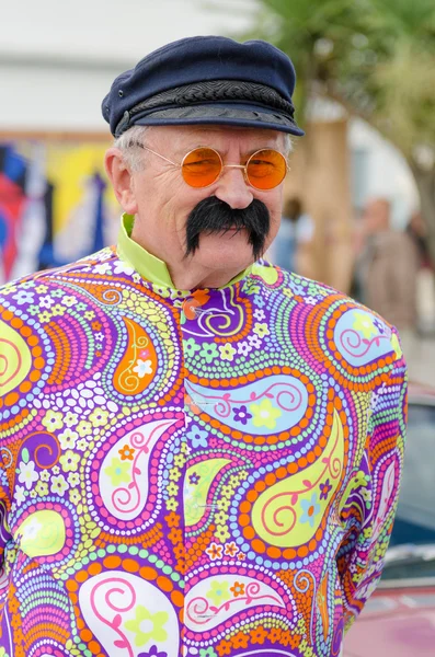 England, morecambe, 16.08.2015, vintage by the sea weekend im midland hotel. Psychedelischer Hippie in Technicolor-Jacke mit rosafarbener Brille. — Stockfoto