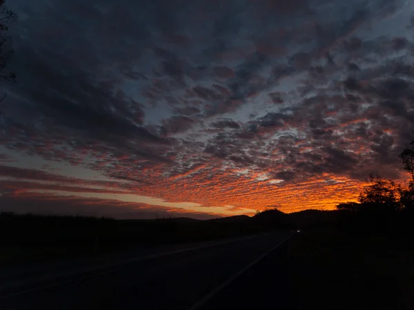 Dramática puesta de sol oscura como el fuego en el cielo con nubes atmosféricas oscuras — Foto de Stock