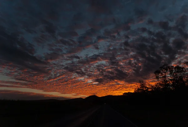 Coucher de soleil noir dramatique comme un feu dans le ciel avec des nuages atmosphériques sombres — Photo