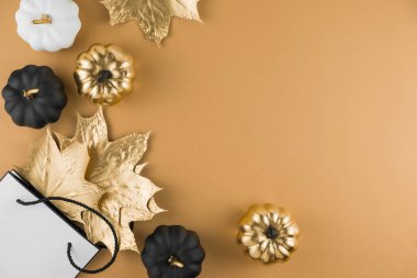 Altın akçaağaç yapraklı sonbahar kompozisyonu, dekoratif balkabakları ve çıplak arka planda alışveriş torbası. Mevsimlik sonbahar indirimi, Kara Cuma. Düz konum, üst görünüm, kopyalama alanı.