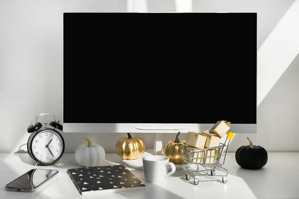 Computadora de escritorio de pantalla en blanco en la moderna sala de oficina mínima con decoraciones de otoño. Cajas de papel en un carro en el escritorio. Concepto de compras online — Foto de Stock