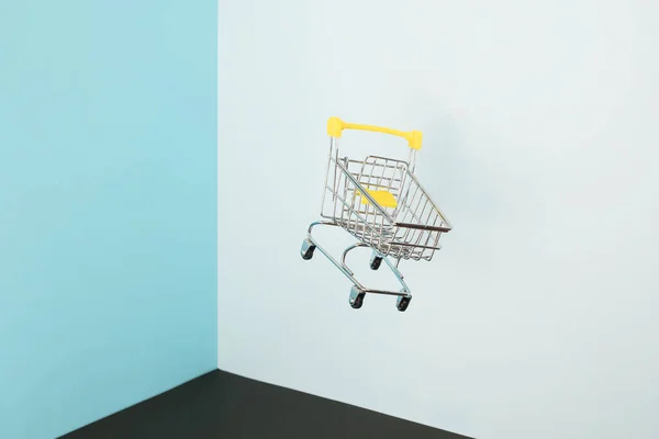 Schwebender Einkaufswagen auf blauem Hintergrund. Sicheres Online-Shopping auf Quarantäne-Konzept. Fliegender leerer Supermarkt-Einkaufswagen mit Kopierraum — Stockfoto