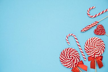 Noel kırmızı çizgili baston şekerler ve mavi arka planda lolipoplar. Mutlu Noeller ve mutlu yıllar konsepti. Flatlay, boşluğu kopyala