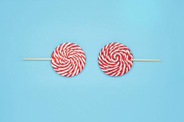 Mavi arka planda şeker kırmızısı lolipoplardan yapılmış komik bir Noel suratı. Mutlu Noeller tatlılar ve mutlu yıllar konsepti