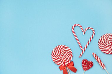 Noel kırmızı çizgili baston şekerler ve mavi arka planda lolipoplar. Mutlu Noeller ve mutlu yıllar konsepti. Flatlay, boşluğu kopyala