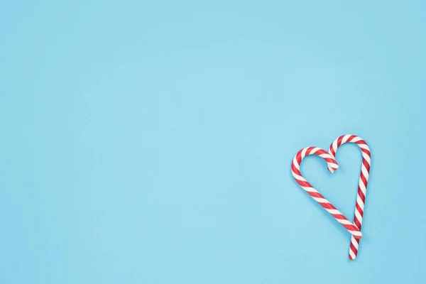 Heart made of candy canes on blue background. Minimal love concept. Space for text. — Stock Photo, Image