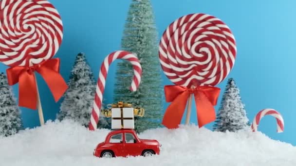 Rode Santa auto met in de kerstboom bos met snoepjes en lolly 's snoepjes. Vrolijk Kerstfeest en Gelukkig Nieuwjaar — Stockvideo