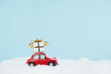 Mavi karlı manzaralı hediye kutusu olan kırmızı bir Noel arabası. Mesaj için yer var. Mutlu yıllar kartı konsepti