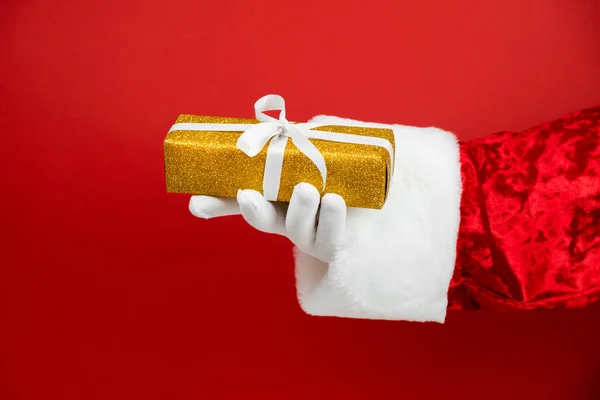 Рука Санта Клауса Блестящей Золотой Подарочной Коробкой Красном Фоне Рождественский — стоковое фото