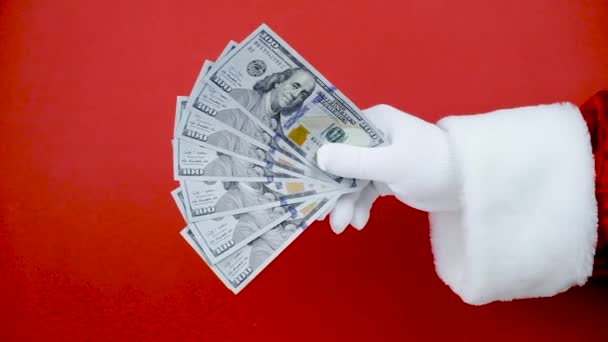 圣诞老人的手把钱扔到空中的红色背景。交现金. — 图库视频影像