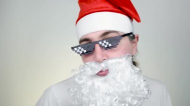 Beyaz arka planda komik pikselli güneş gözlükleriyle dans eden Tarz Noel Baba. Gangster, patron, cani hayatı. 8bit tarzı. Holly Jolly x Mas Noel. Parti zamanı, Mutlu yıllar, Mutlu Noeller