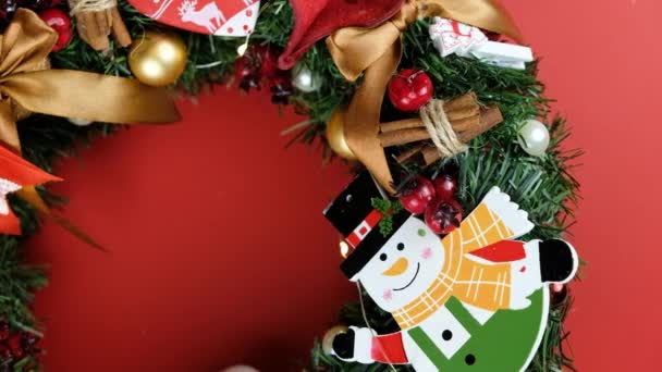 Mooie hand van Kerstmis gemaakt rustieke krans op rode achtergrond. Gemaakt met dennenappels, ballen en bladeren — Stockvideo
