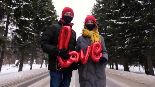 戴着防护面罩的夫妻流行病流行期间在公共场所采取的保护措施。Covid St. Valentine假日庆祝活动 — 图库视频影像